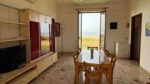 A spacious living area with a dining table, TV, and built-in shelving.