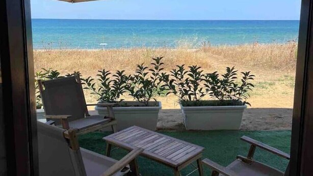 A patio with a view of the ocean, featuring a table, chairs, and a large umbrella.