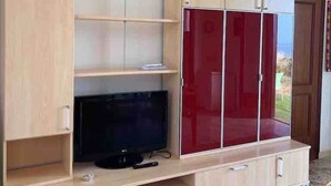 A room with a wooden TV stand, a flat-screen TV, and a red cabinet.