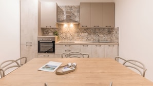 A modern kitchen with a built-in oven, a sink, and a dining table with chairs. - Charming 2BR in Historic Valletta | Prime Central Location (Valletta)