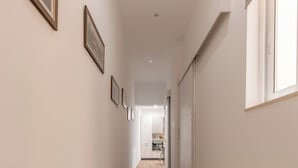 A hallway with wooden flooring, white walls, and framed pictures. - Charming 2BR in Historic Valletta | Prime Central Location (Valletta)