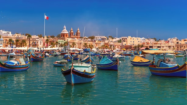 A harbor with numerous boats, a flag, and a historic building in the background. - Charming 2BR in Historic Valletta | Prime Central Location (Valletta)
