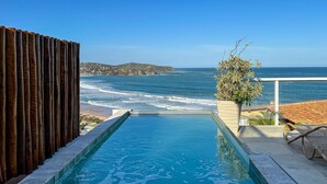Une piscine avec vue sur l’océan et une clôture en bois.