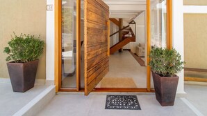 Une porte en bois donne sur un escalier, et de chaque côté, on trouve un pot de fleurs.