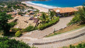 Une ville côtière aux bâtiments aux toits de tuiles rouges, avec une plage et une vue dégagée sur l’océan.