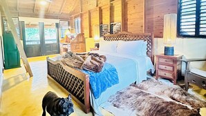 Ein geräumiges Zimmer mit einem großen Bett, Holzwänden, einem Deckenventilator und Blick ins Freie.