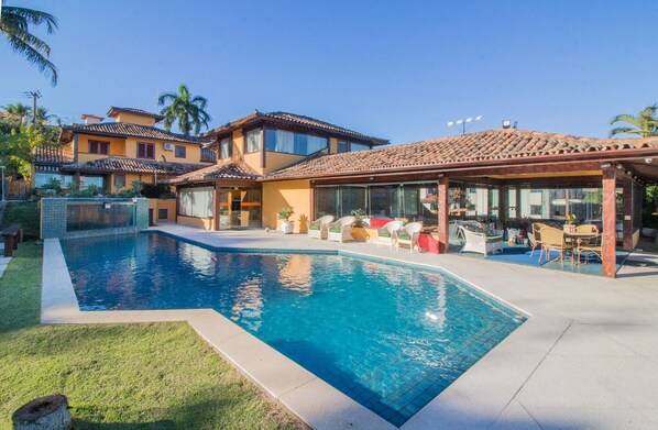 A modern house with a swimming pool, a covered patio, and a well-maintained garden. - Cinematográfica Mansão Pé na Areia  (Búzios)