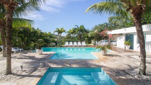 A pool area with two rectangular pools, surrounded by palm trees and lounge chairs. - Harmoniosa Mansão com 7 Suítes Ferradura (Búzios)