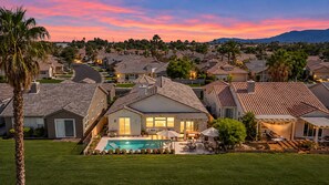 A residential area with houses, a swimming pool, and a sunset sky. - Escape the Cold - Fall & Winter Rates Reduced! (Indio)
