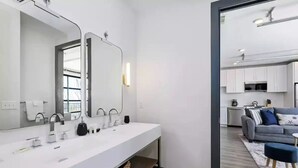 A modern bathroom with a large mirror, white sink, and a wooden shelf. - Muse:5 minutes to broadway

 (Nashville)