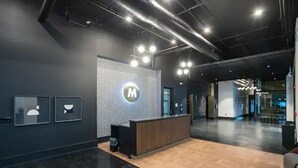 A reception area with a modern design, featuring a reception desk, a logo on the wall, and framed artwork on the wall. - Muse:5 minutes to broadway

 (Nashville)
