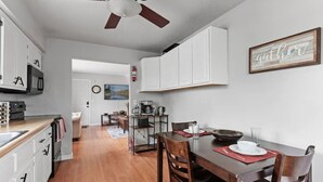 A modern kitchen with white cabinets, a dining area with wooden chairs, and a ceiling fan. - Tranquil 2BR Apt Mpls - 8075 Apt 3 (Minneapolis)