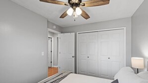 A bedroom with a ceiling fan, a bed, a nightstand, and a door leading to another room. - Tranquil 2BR Apt Mpls - 8075 Apt 3 (Minneapolis)