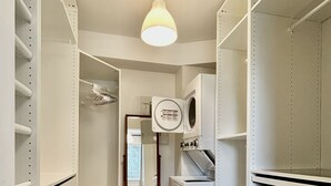 A laundry room with a washing machine, dryer, and shelving units.