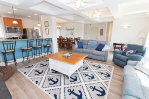 A spacious living area with a dining table, sofas, and a kitchen in the background.