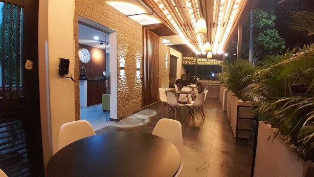 Un espacio interior moderno con una mesa redonda y sillas, un muro de ladrillo y un cartel que indica servicios de internet.
