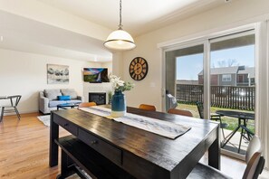 A modern dining area with a wooden table, bench seating, and a vase with flowers. - Executive Townhouse To Stay (Colorado Springs)
