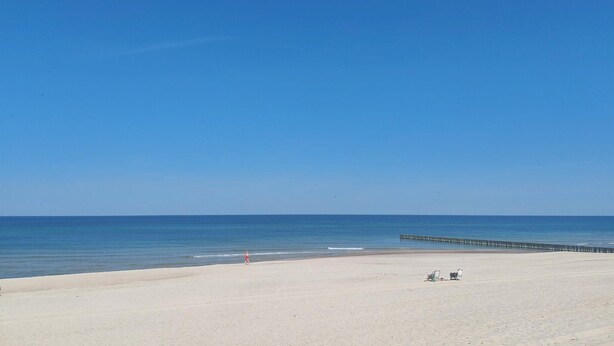 A beach with a clear sky, a sandy shore, and a pier extending into the water. - 1 bedroom amazing home in Ustronie Morskie (Ustronie Morskie)