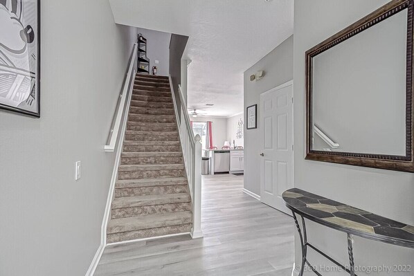 A staircase leading to a kitchen area with white cabinets and a red appliance.