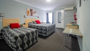 A hotel room with two beds, a small table, a mirror, and a window. - Gundagai Motel (Gundagai)