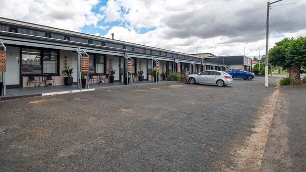 A row of motel rooms with individual entrances, a parking area, and a clear sky. - Gundagai Motel (Gundagai)