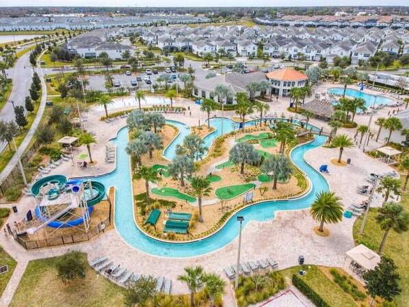Vue aérienne d’un complexe hôtelier doté d’une grande piscine, d’un toboggan aquatique et d’un parcours de golf.