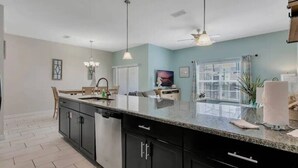 A modern kitchen with a large island, dark cabinetry, and pendant lighting. - Storey Lake Peaceful Townhome with Private Pool (Kissimmee)