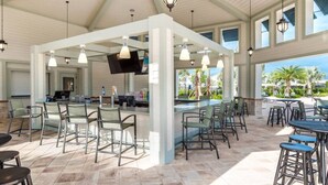 A covered outdoor bar area with seating, a counter, and a TV screen. - Storey Lake Peaceful Townhome with Private Pool (Kissimmee)