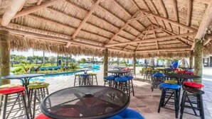 An outdoor seating area with thatched roof, tables, and colorful chairs. - Storey Lake Peaceful Townhome with Private Pool (Kissimmee)
