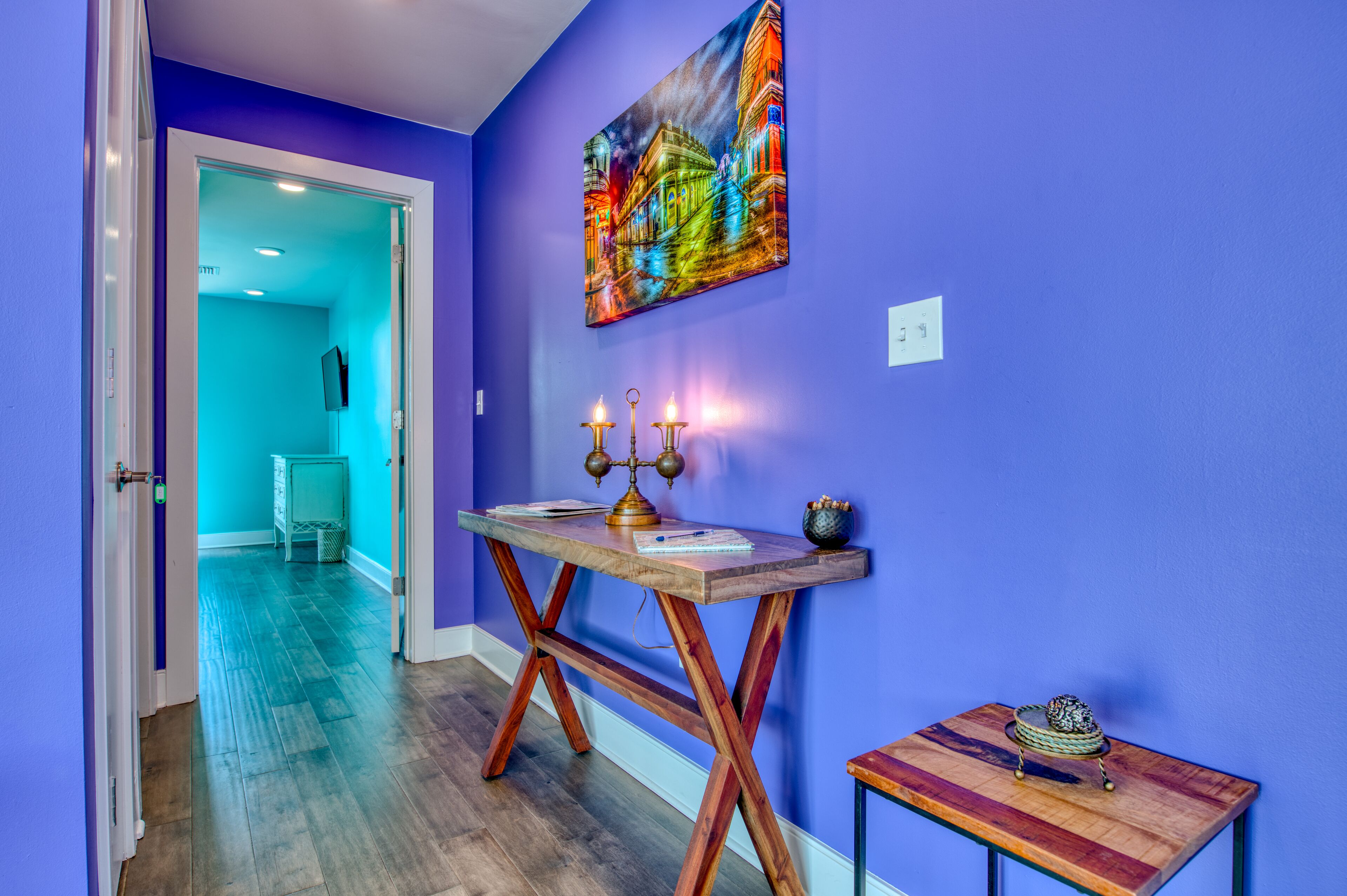 A hallway with a blue wall, a wooden table with candles, and a small table with a decorative item.