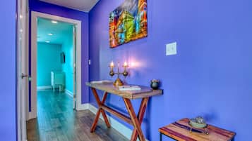 A hallway with a blue wall, a wooden table with candles, and a small table with a decorative item.