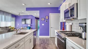 A modern kitchen with white cabinets, a built-in microwave, and a gas stove.