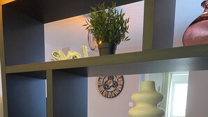 Un interior moderno con una paleta de colores negro y gris, que incluye una planta decorativa, un cuenco de vidrio con flores secas y un reloj de pared.