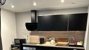 Una cocina moderna con una mesa redonda de cristal, un barril de madera y una silla.