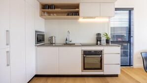 A modern kitchen with white cabinetry, a built-in oven, a microwave, and a sink. - Luxury 3 Bedroom Wanaka Townhouse (Albert Town)