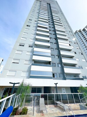 A high-rise building with multiple balconies and a swimming pool area with sun loungers. - Apto Moderno com Vista Fantástica do Flamboyant (Goiânia)