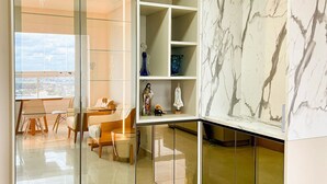 A modern room with a glass partition, a dining area with chairs and a table, and a marble wall. - Apto Moderno com Vista Fantástica do Flamboyant (Goiânia)