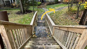 Una escalera de madera que lleva a una casa con jardín.