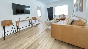 A modern living room with a sofa, two chairs, a coffee table, and a TV mounted on the wall. - 4173-Newly renovated stylish home (San Diego)