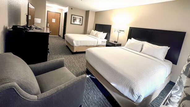 A hotel room with two beds, a desk, a chair, and a lamp. - Country Trails Inn & Suites  (Preston)