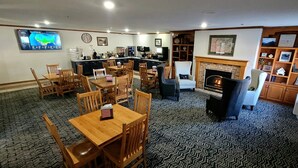A hotel lobby with a dining area, a fireplace, and a television displaying a map. - Country Trails Inn & Suites  (Preston)