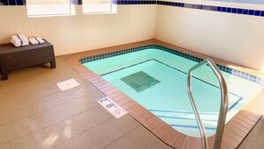 A swimming pool with a capacity sign, a lifeguard warning sign, and a spa rules sign. - Country Trails Inn & Suites  (Preston)