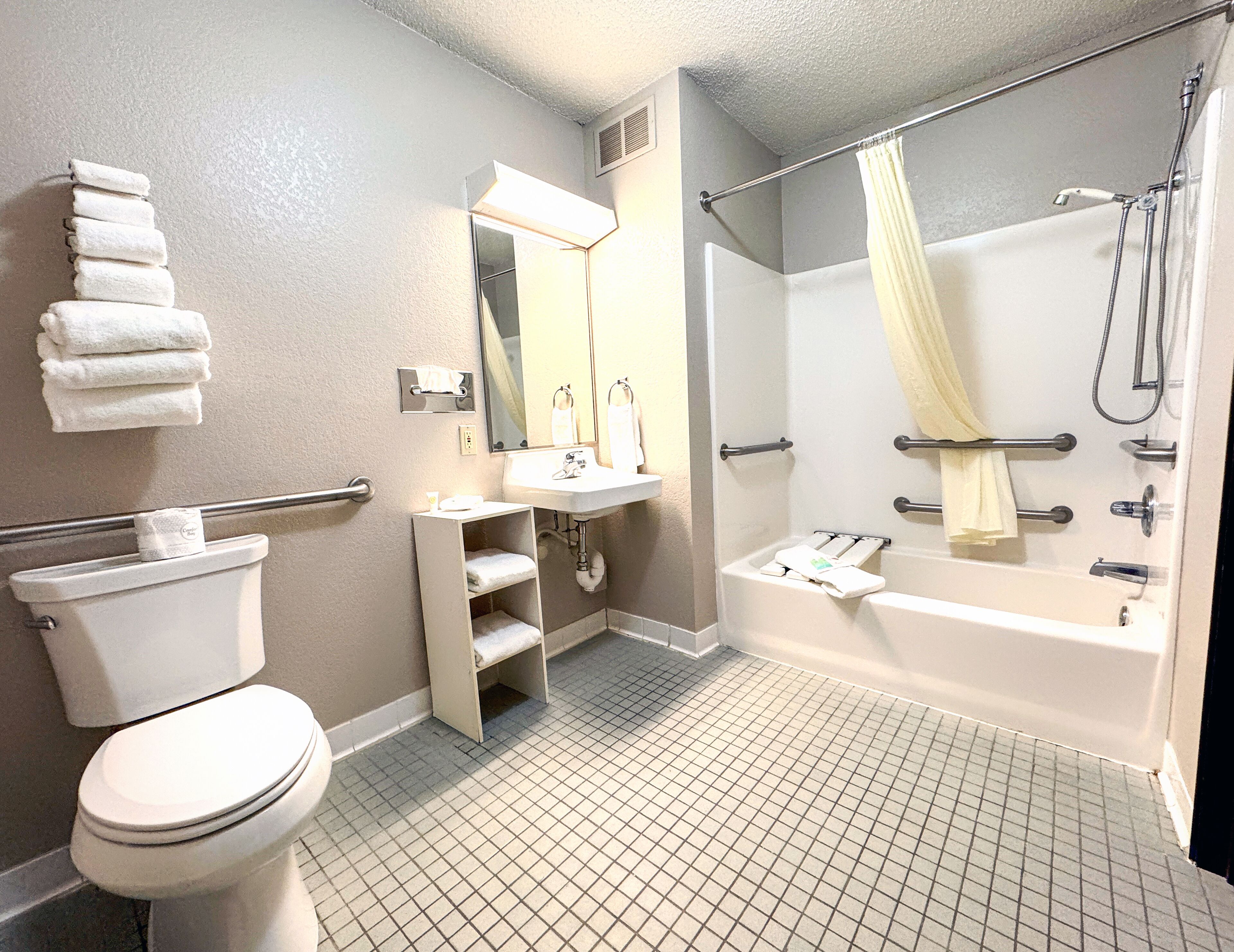 A bathroom with a toilet, sink, mirror, shower, and a towel rack.