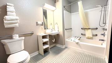 A bathroom with a toilet, sink, mirror, shower, and a towel rack.