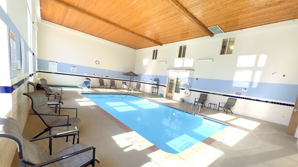 A swimming pool with lounge chairs and a ceiling with wooden beams.