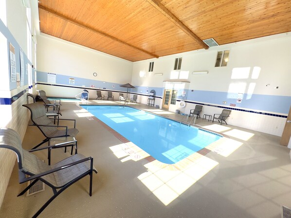 A swimming pool with lounge chairs and a ceiling with wooden beams.
