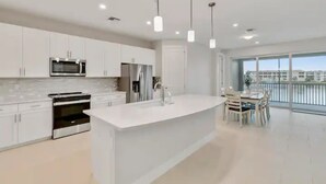 Una cocina moderna con armarios blancos, electrodomésticos de acero inoxidable y una isla grande.