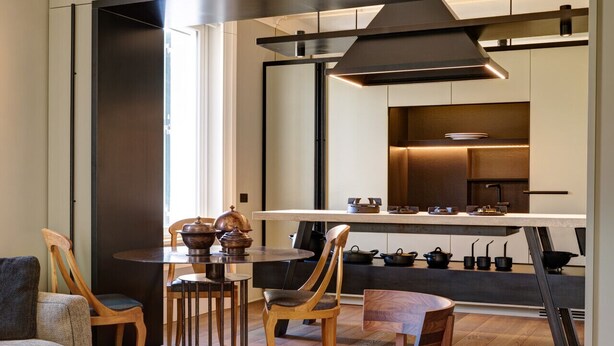 A modern kitchen with a central island, wooden chairs, and a dining table. - Mastroianni House with Terrace by Hostalia (Roma)
