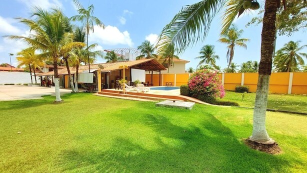 A residential property with a swimming pool, palm trees, and a well-maintained lawn. - Aconchego do Caranã (Salinópolis)