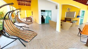 A spacious indoor area with a yellow and white color scheme, featuring wicker furniture and a tiled floor. - Aconchego do Caranã (Salinópolis)